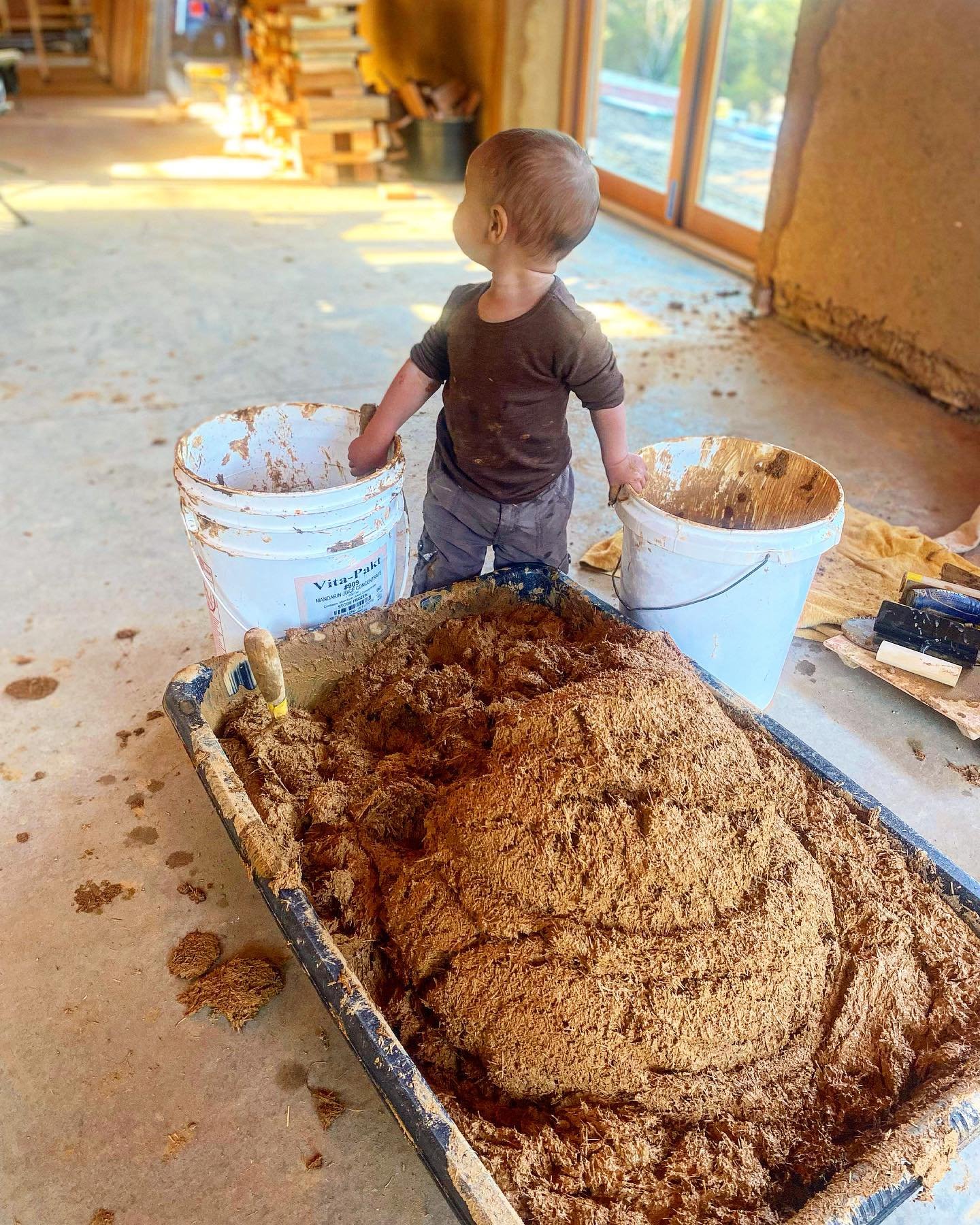 My favorite assistant. It&rsquo;s super convenient that we have buckets of mud around for our work, he doesn&rsquo;t even notice the power tools.
 #babyonthejob #earthenbuilding #earthenplaster