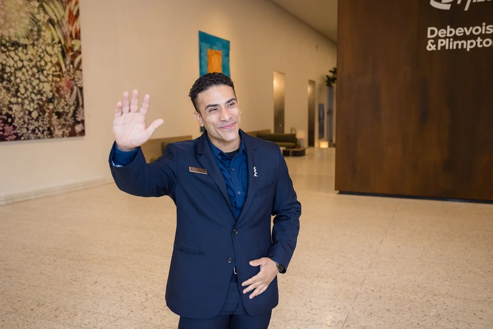 Hotel executive waving in a modern lobby for corporate branding photography