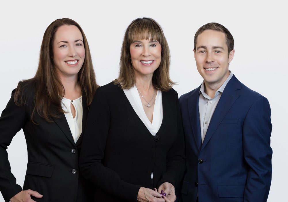 Group headshot of three colleagues in business attire on a white background