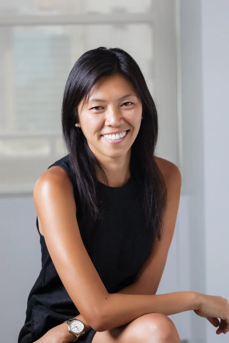 On-location headshot of a smiling woman in a sleeveless black top seated in an office