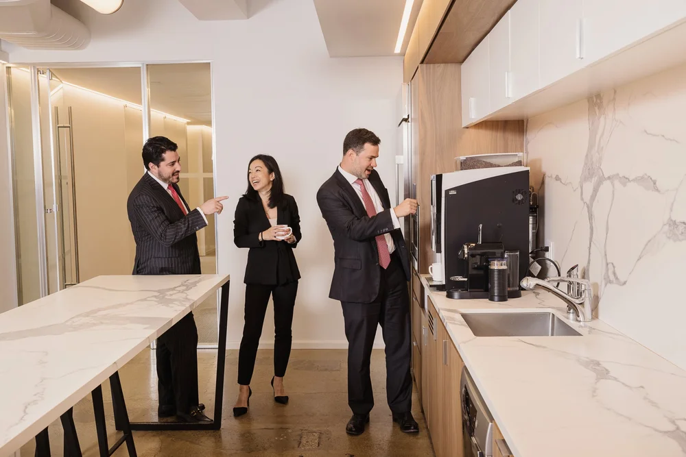 Corporate culture photography of three professionals having coffee in a modern office kitchen