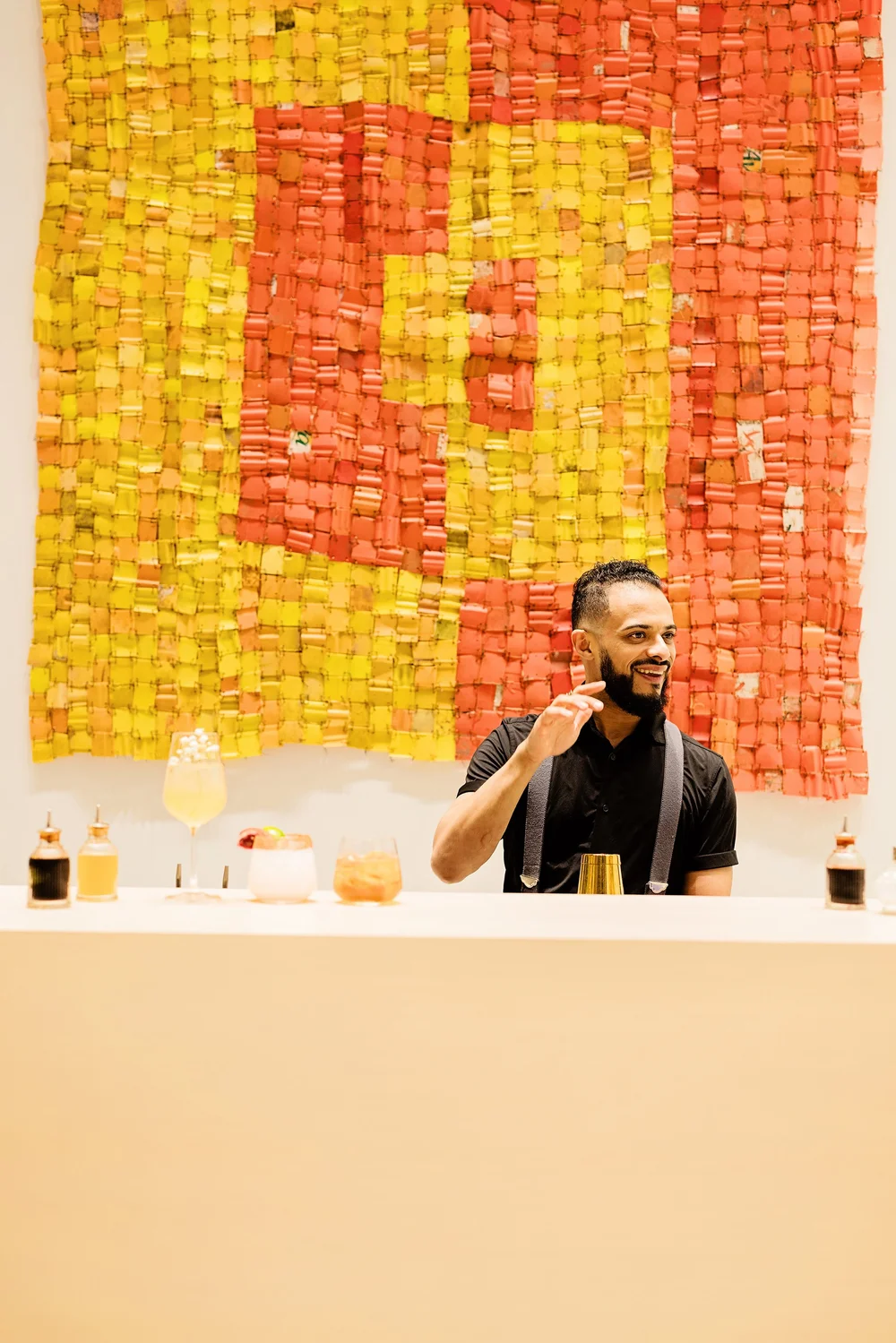 Smiling bartender in front of a colorful art wall at a corporate event