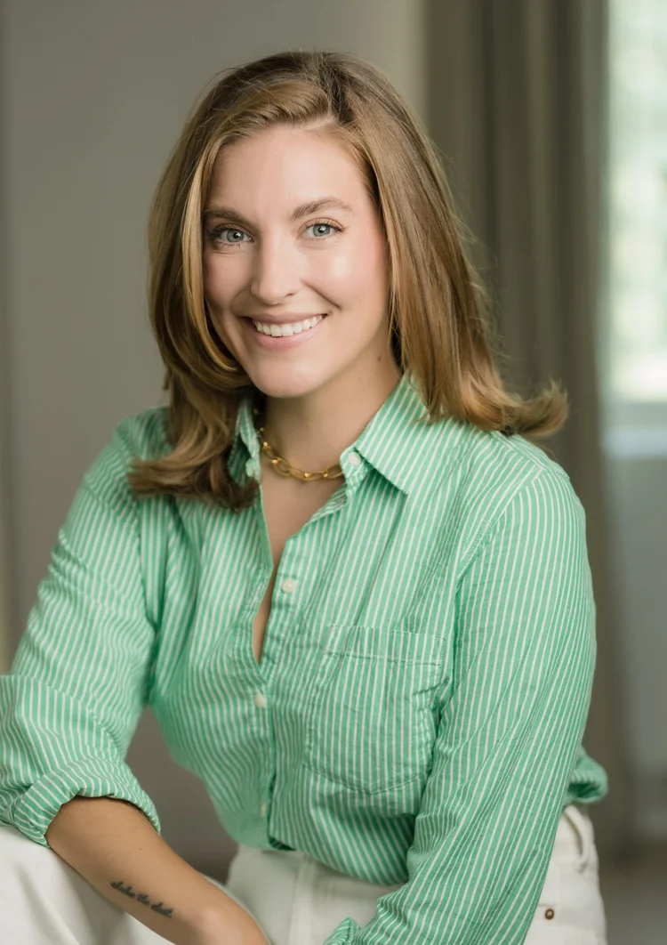 Casual headshot of a smiling woman in a green striped shirt in a softly lit room