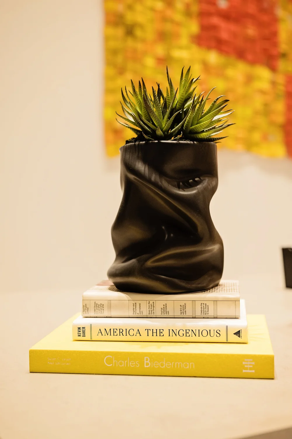 Styled detail of a sculptural vase with a succulent on stacked books for brand content photography