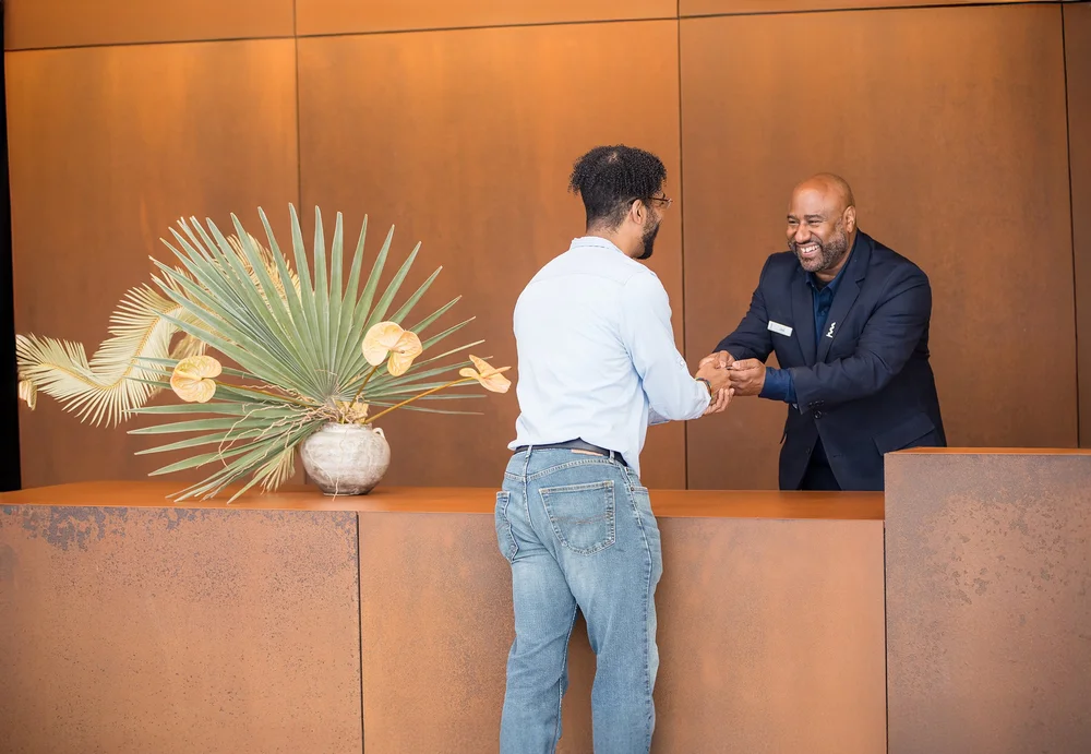 Hotel manager greeting a guest at the front desk during a brand photography session