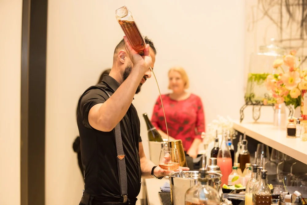 Bartender pouring a pink cocktail at an evening event for brand content