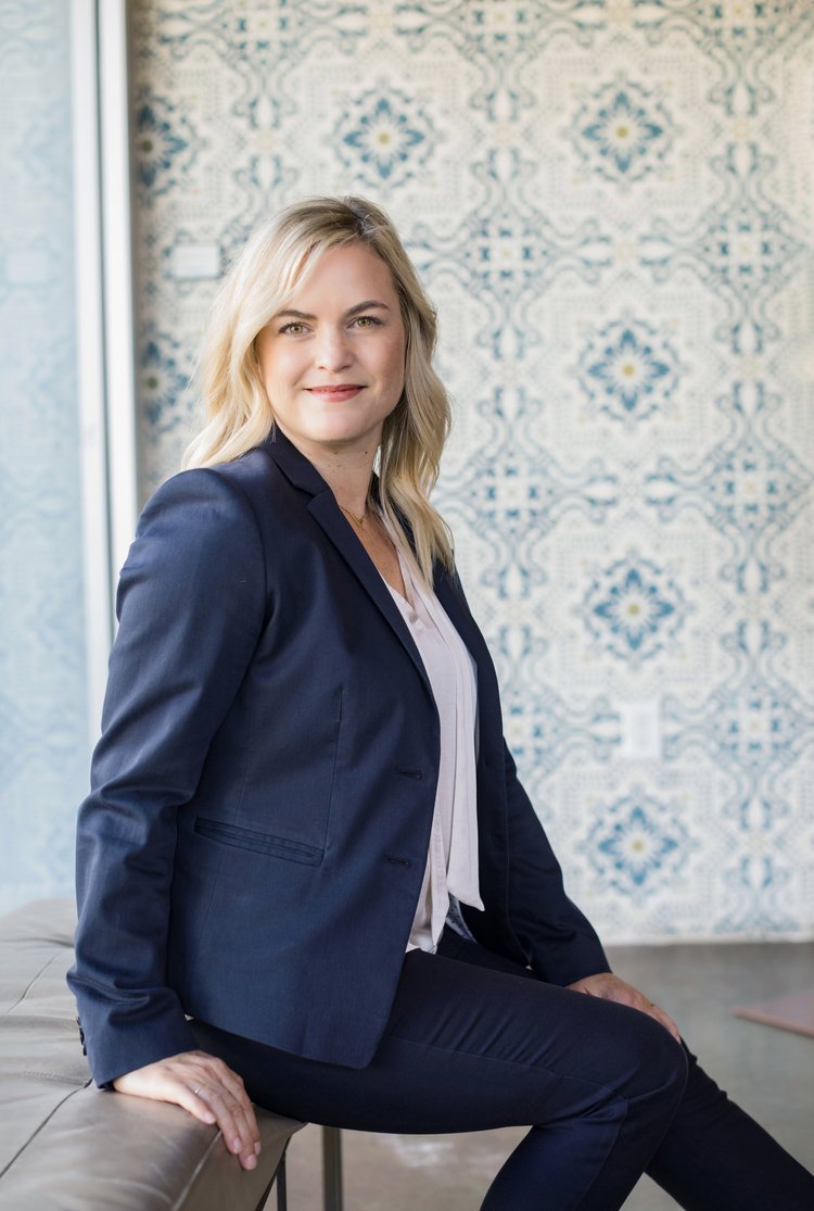 Branding portrait of a woman in a navy blazer seated in front of a patterned tile wall