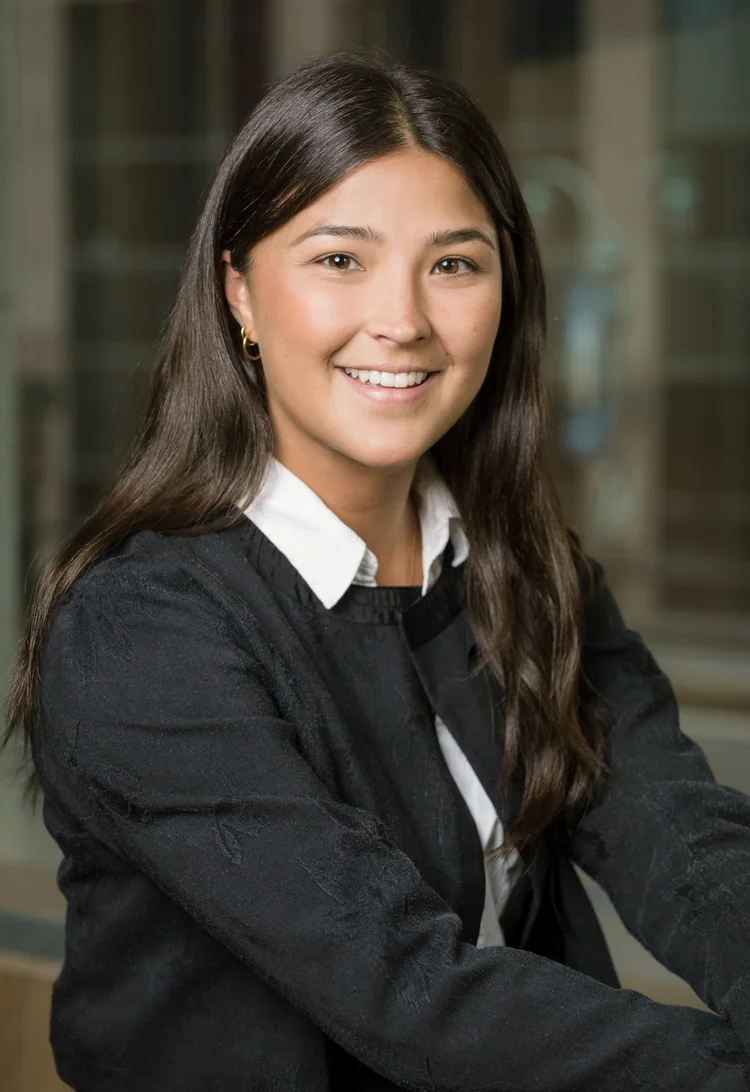 On-location headshot of a smiling young woman in a black blazer in an office