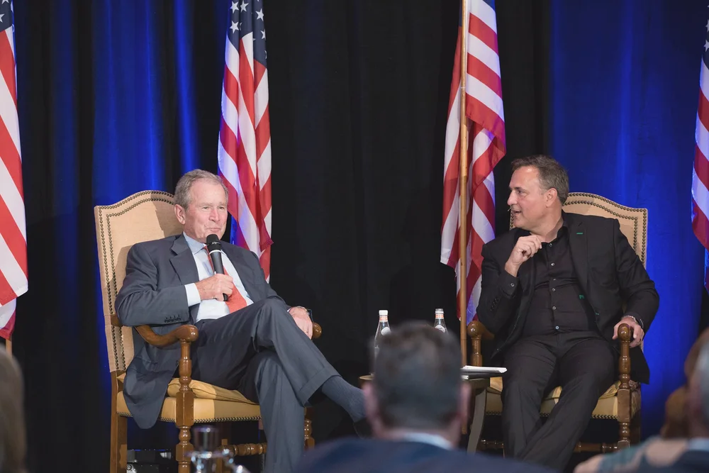 Fireside chat on stage in front of American flags at a corporate event