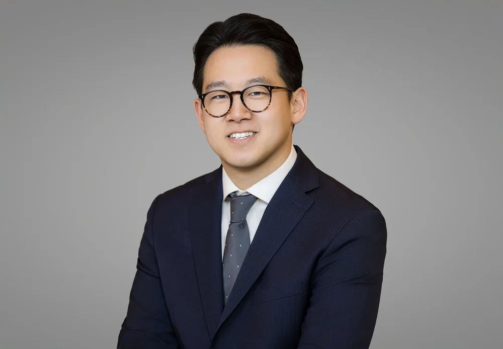 Brand-forward business headshot of a New York professional in glasses on a grey background, by Blue Sky's Studio