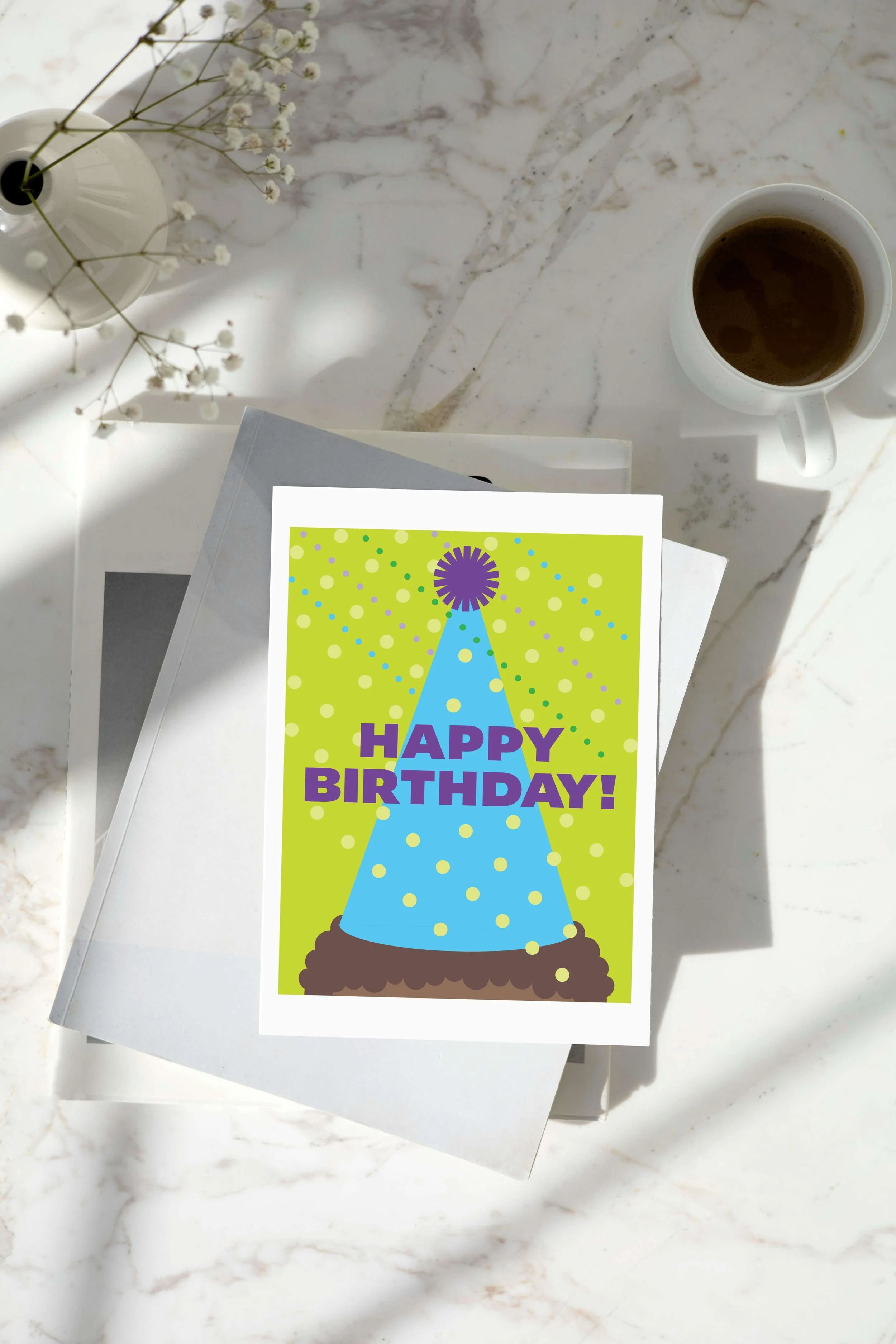 Happy Birthday greeting card. On top of stacked books on marble table with coffee.