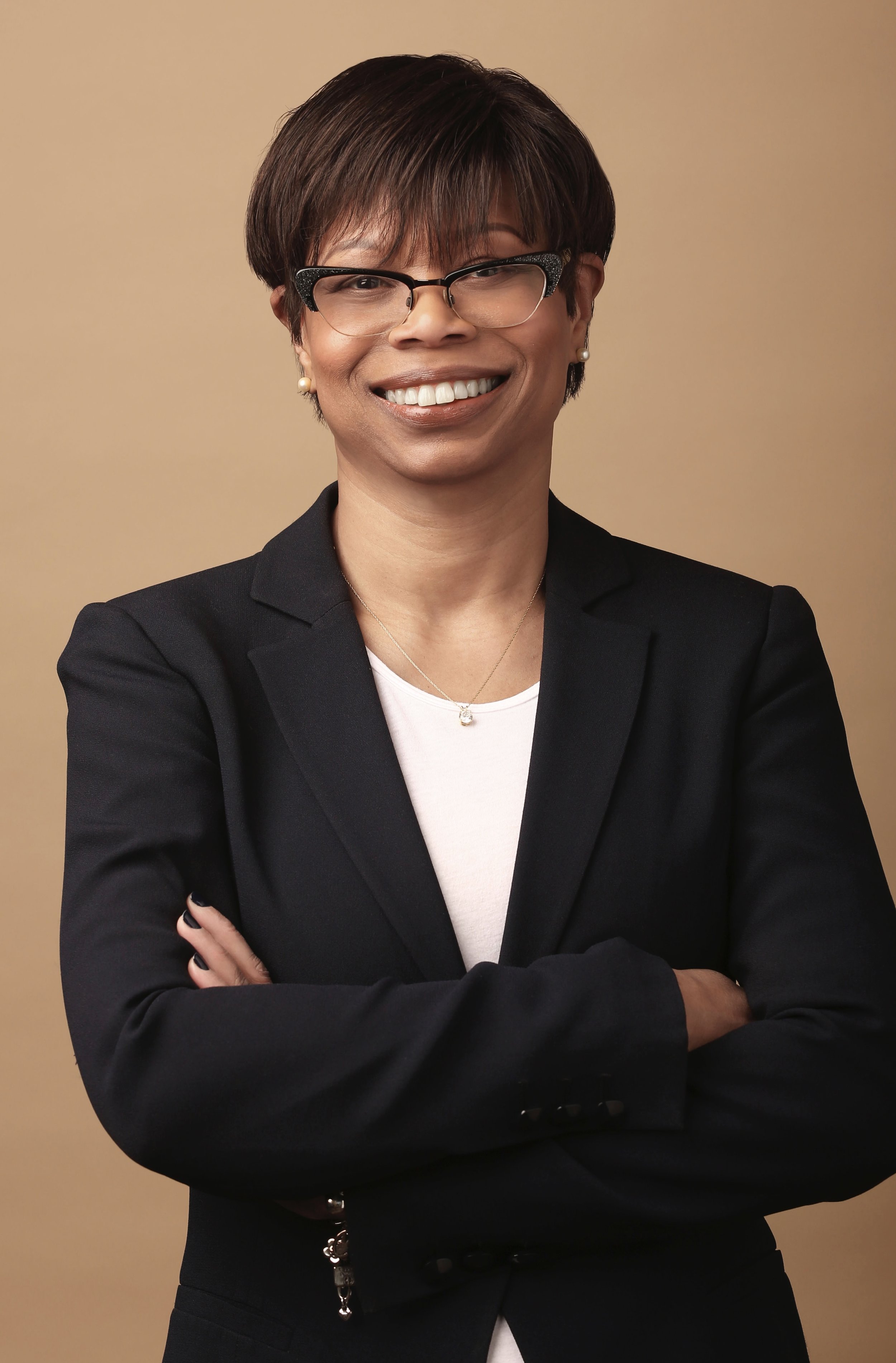 Jackie Monk with back blazer, white shirt in front of brown backdrop