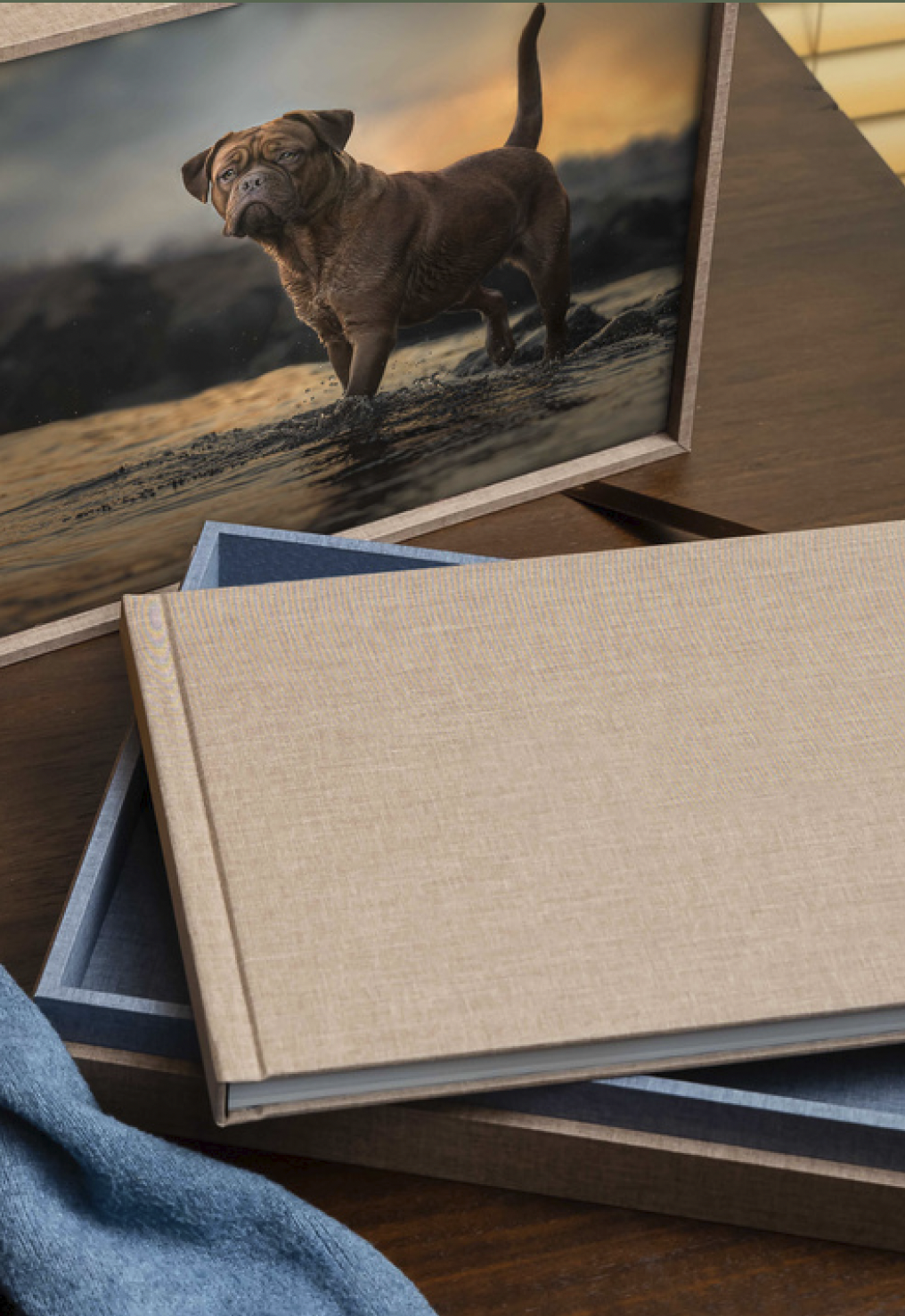 Stacked photo frames with a brown dog picture in foreground and a beige book on a wooden surface.