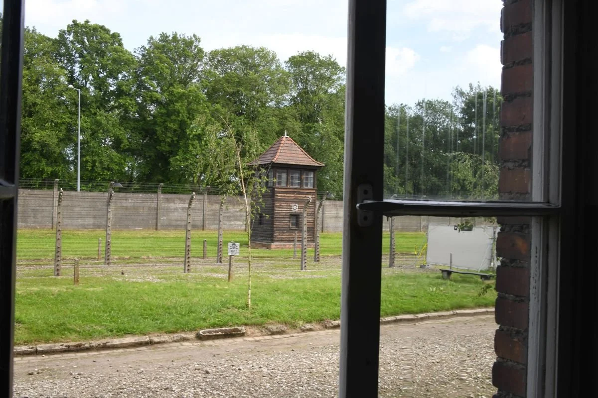 MAC_5499 · Watchtower and fence through a window, Auschwitz I, Poland