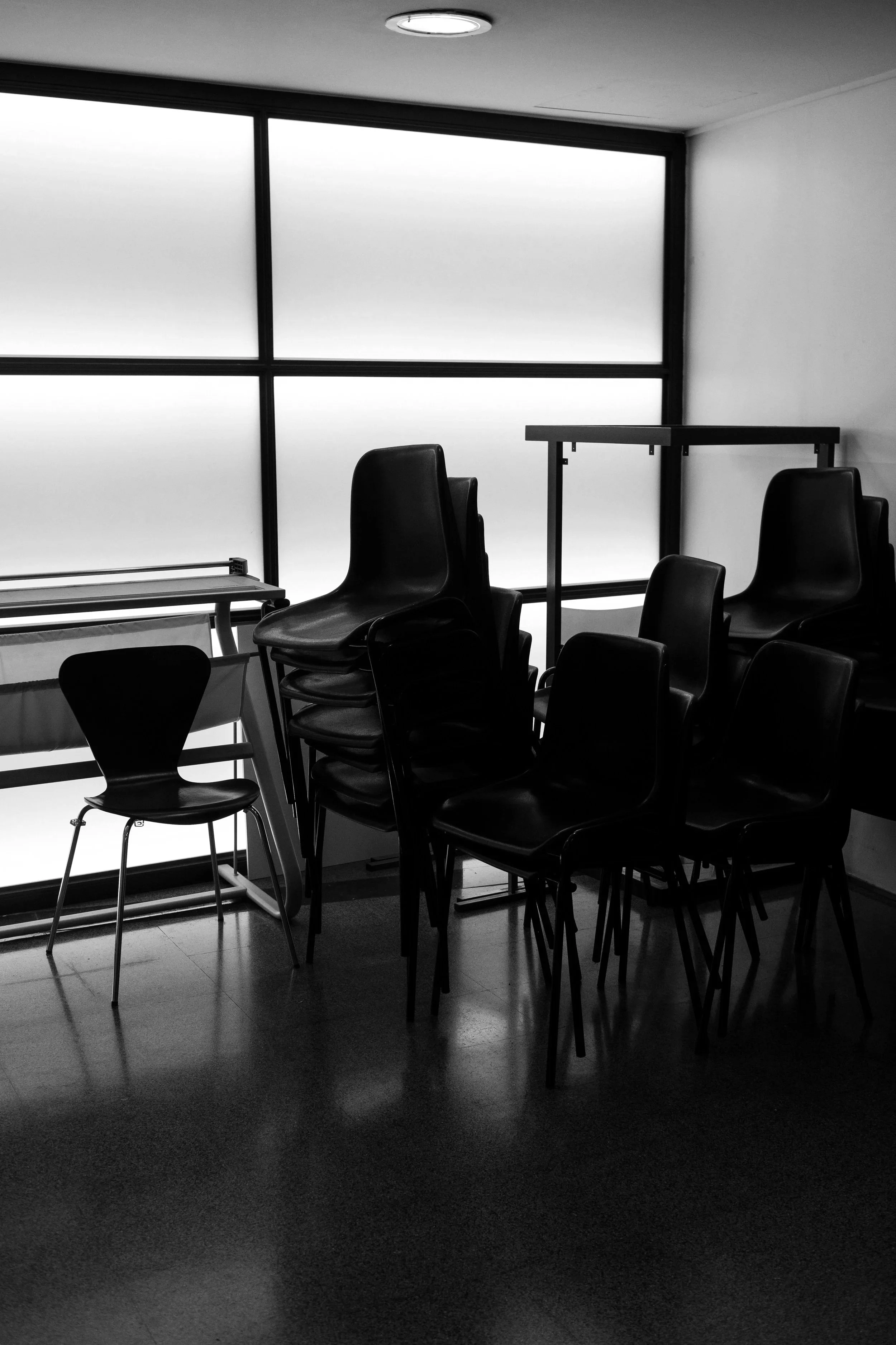 Silhouettes of four people kayaking on a calm body of water, with their reflections visible on the water's surface.