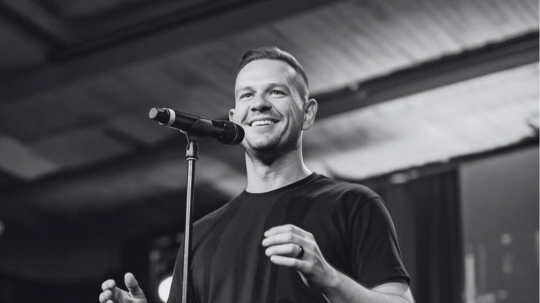 Smiling man speaking into microphone at a stage or studio