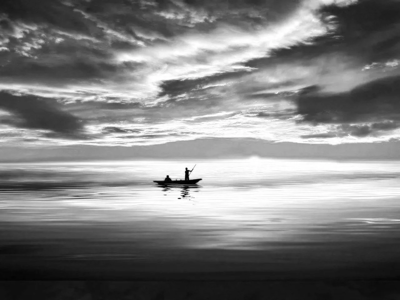 Silhouettes of two people on a boat at sunset, with a dramatic orange and purple sky reflected on calm water.