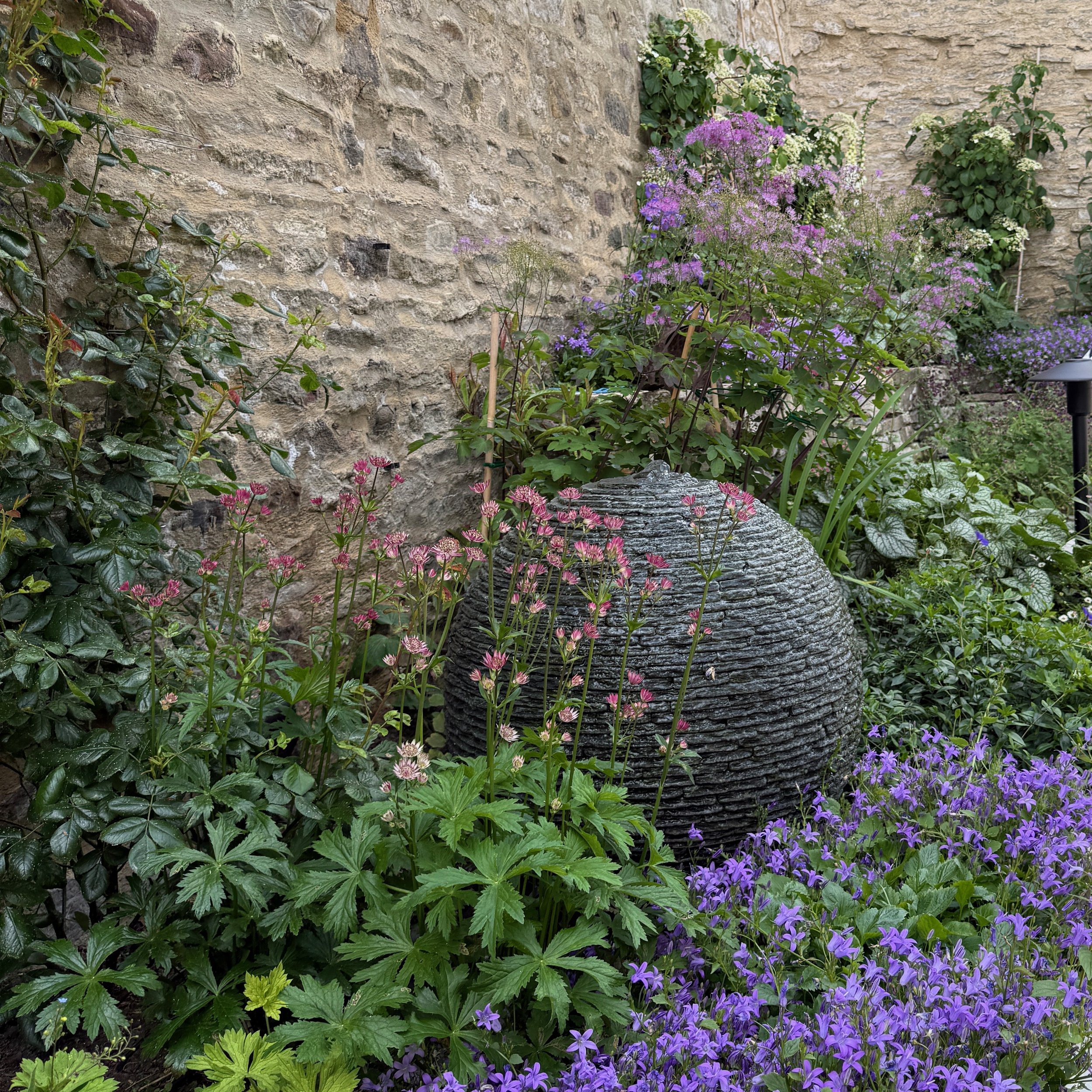 A slate globe water feature nestled among planting for shade