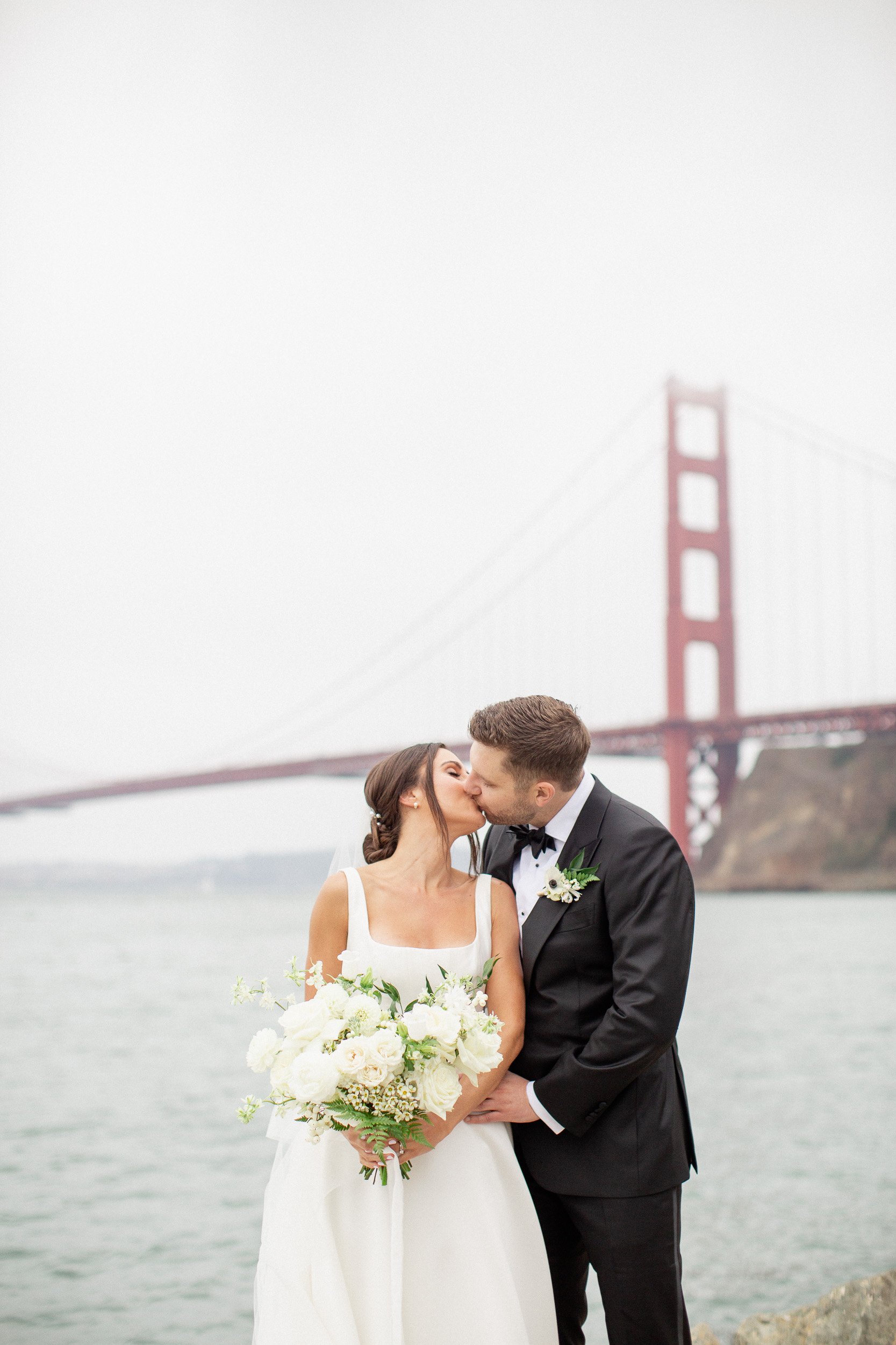 bride and groom kissing during their wedding portraits under the golden gate bridge at the Cavallo Point Marina 