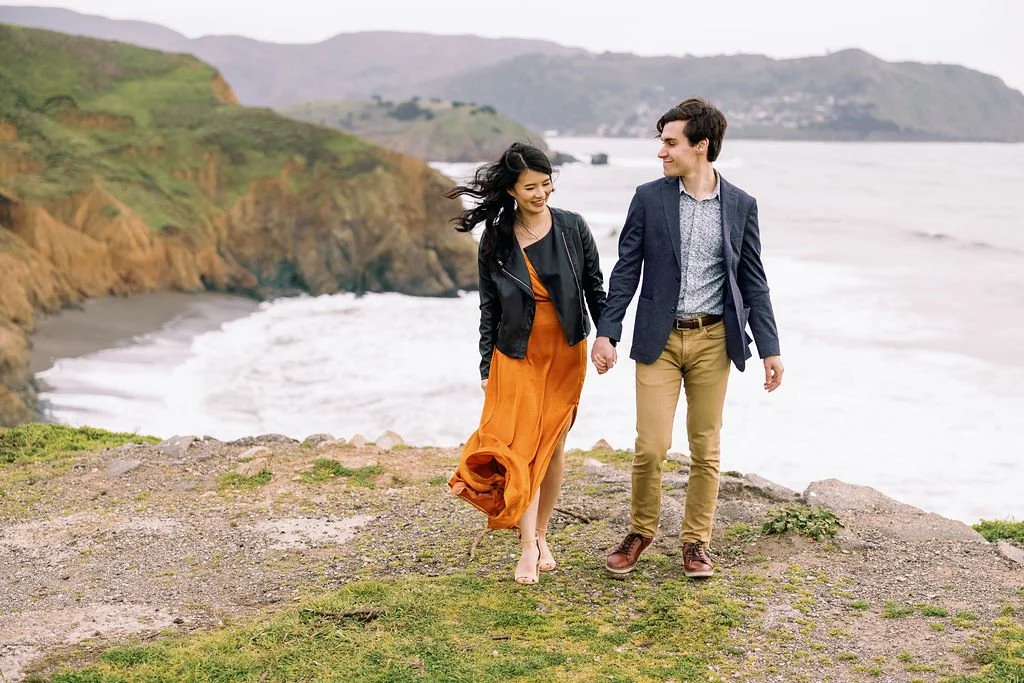  couple walking along the ocean cliff at their engagement session in Mori Pt, Pacifica 