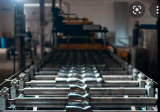 Metal roofing manufacturing equipment with standing seam panels in production, showcasing sleek metal profiles and machinery.