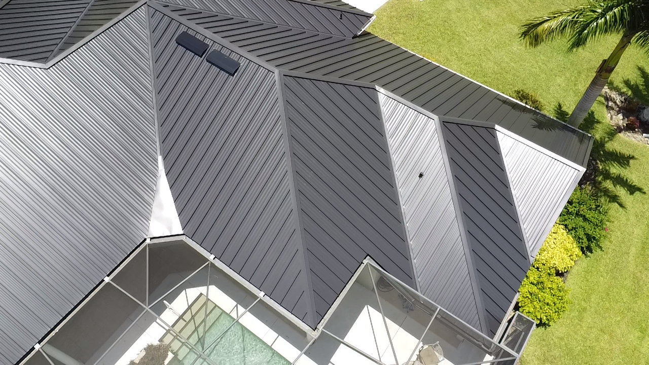 Aerial view of a modern residential home featuring a standing seam metal roof with raised vertical seams, showcasing durability and aesthetic appeal amidst green landscaping.