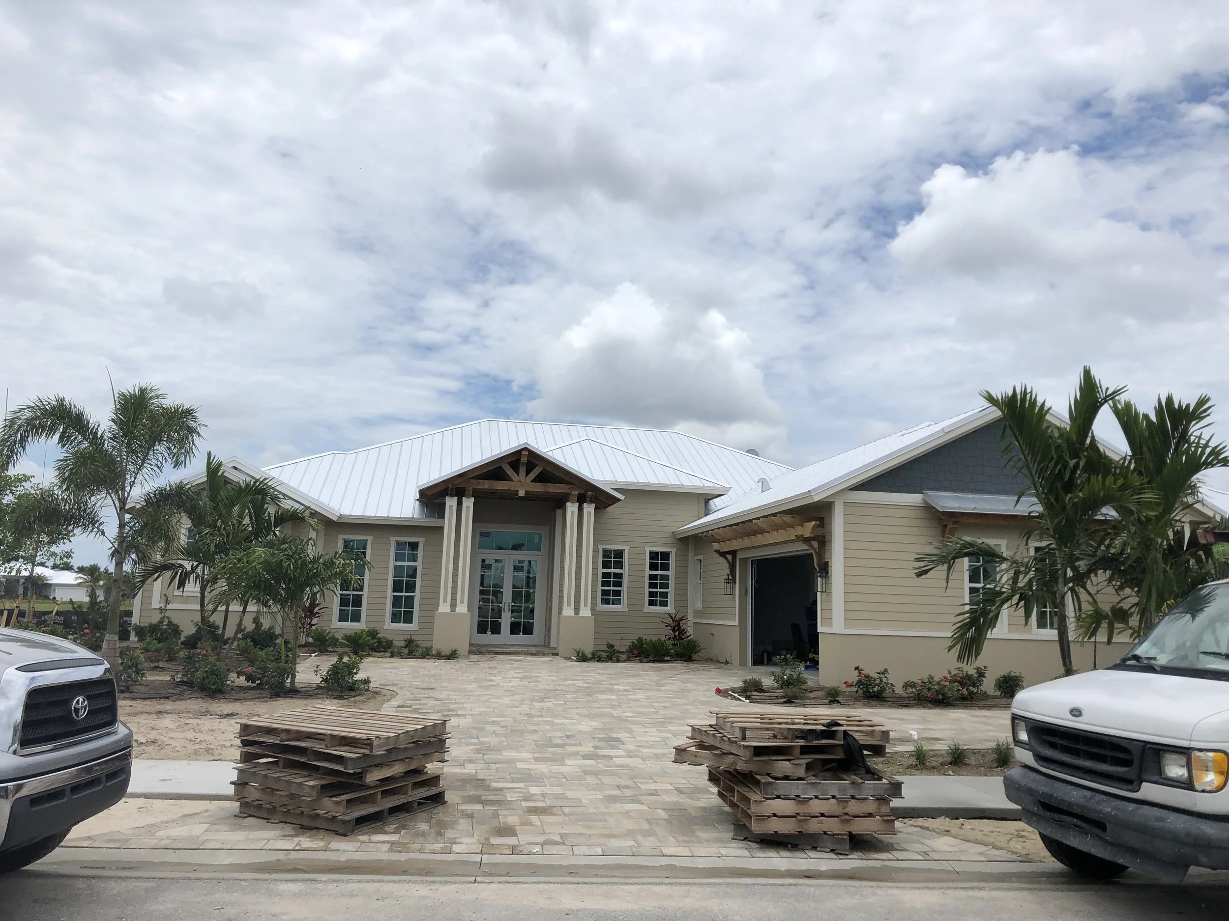 New home with a standing seam metal roof, featuring a modern design, landscaped front yard, and construction materials visible, emphasizing budget-friendly metal roofing solutions.