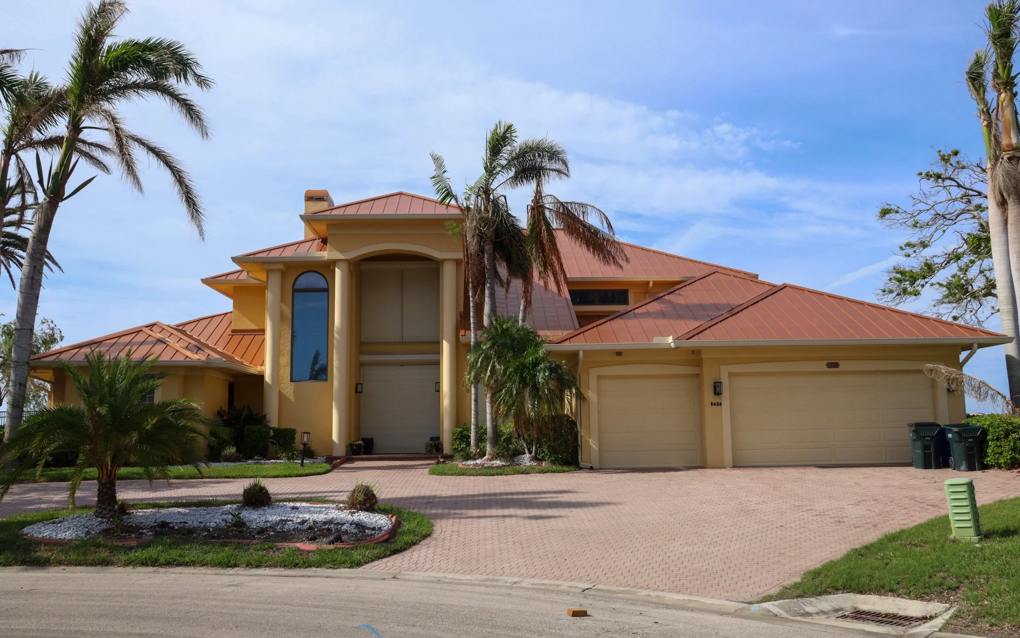 Residential home featuring a durable metal roof, suitable for various climates, surrounded by tropical landscaping and palm trees.