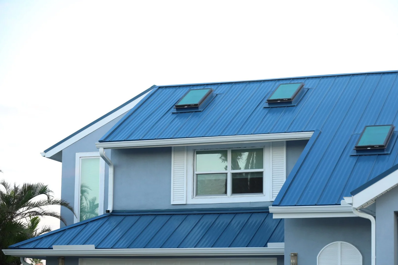 Blue standing seam metal roofing with skylights on a residential building, showcasing a modern aesthetic and durability.