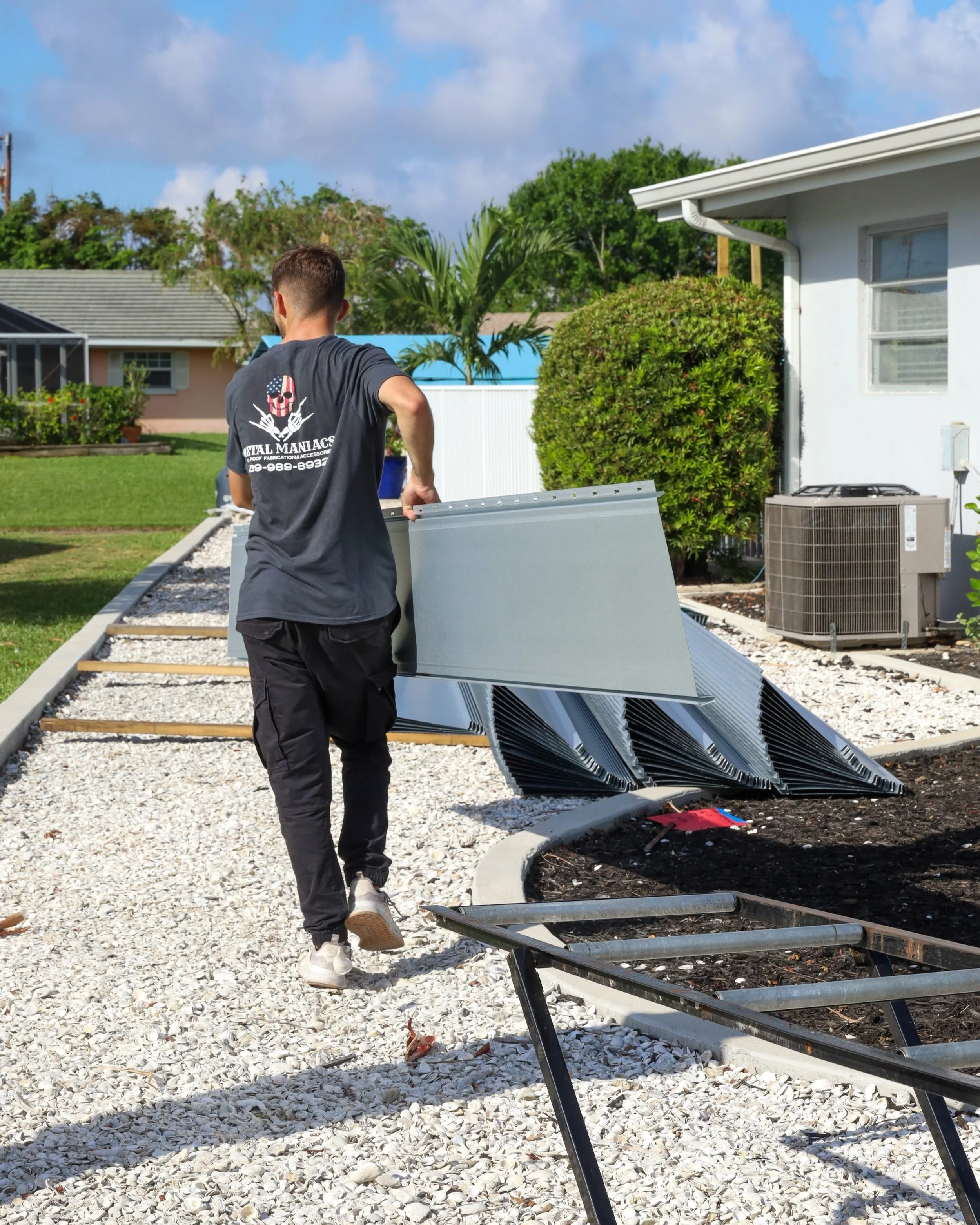 Worker carrying metal roofing panels for installation, showcasing eco-friendly building practices and sustainable home improvements.