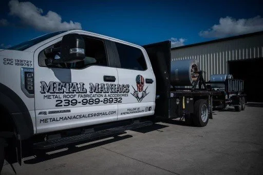 Metal Maniacs branded truck with metal roofing materials and tools, parked outside a facility, emphasizing metal roofing supply services in Fort Myers.