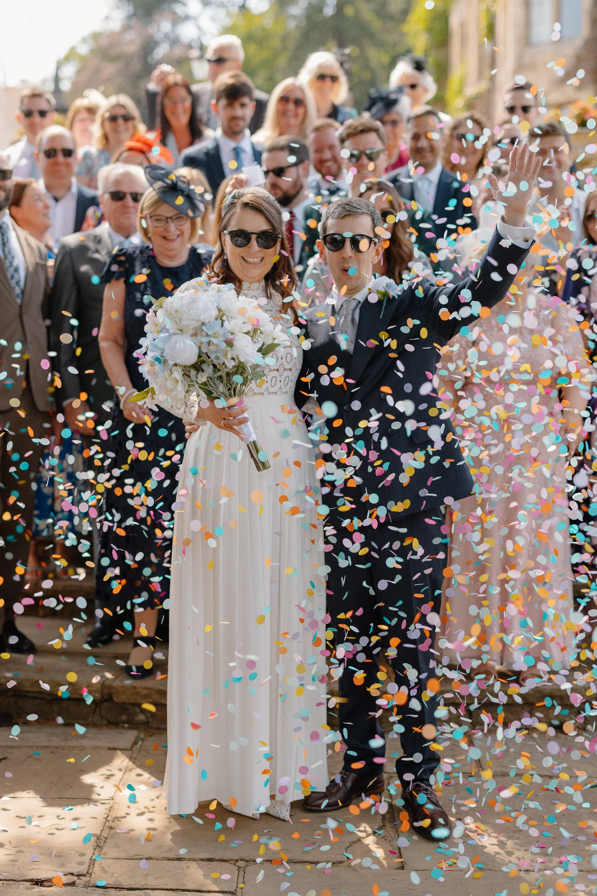 A bride and groom celebrate within a cloud of confetti.