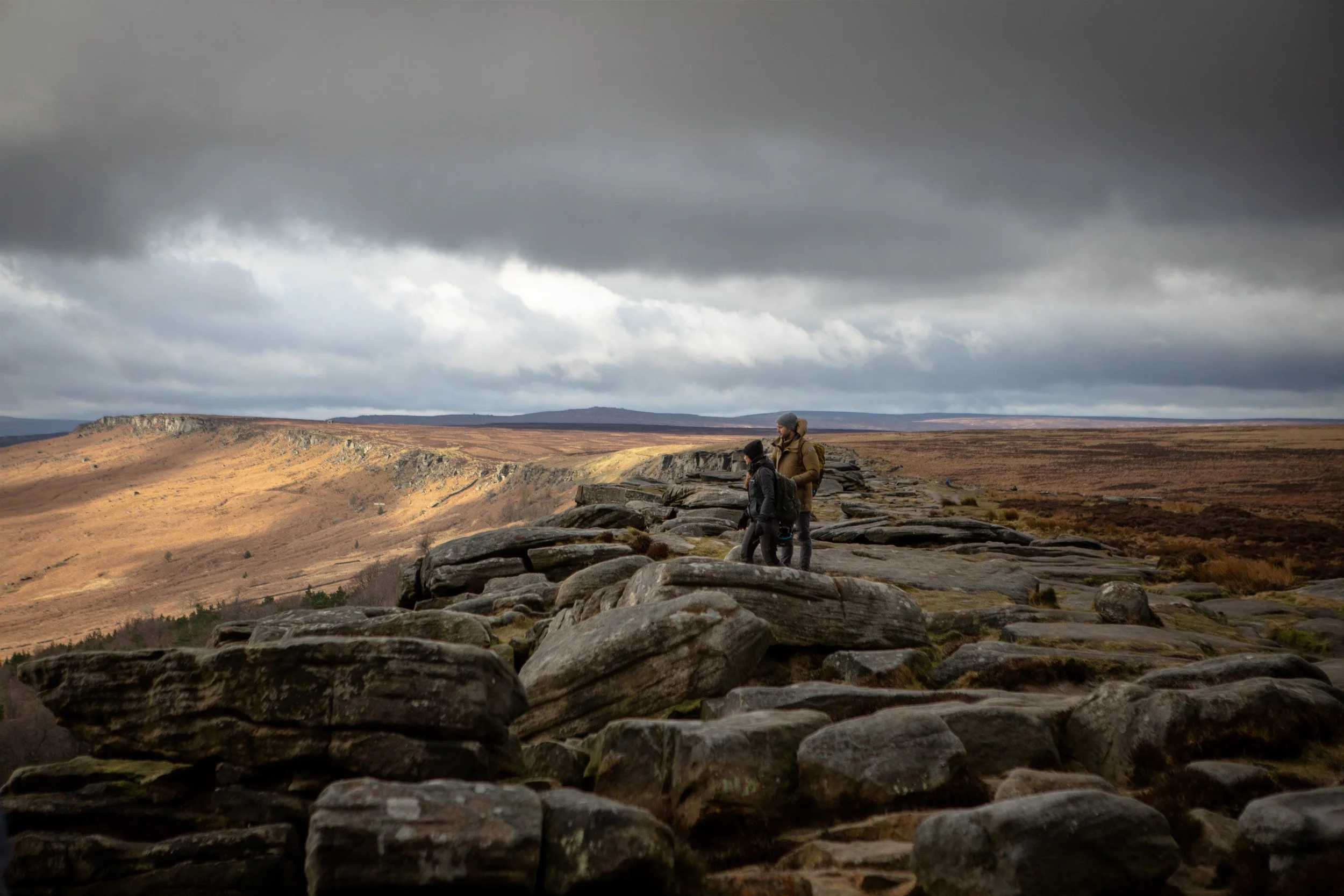 Phil and Jess look upon a valley from atop a stoney cliff-face in Wales.