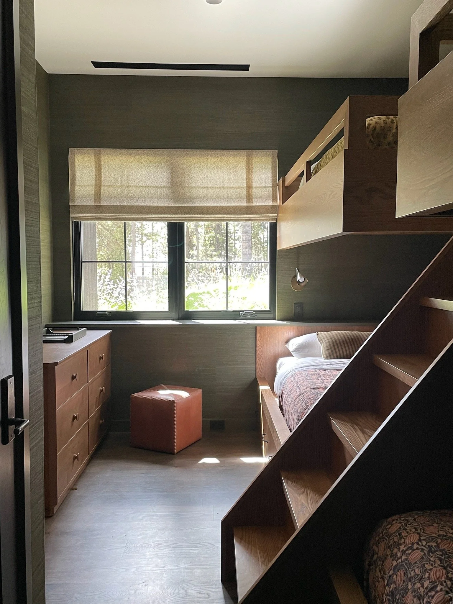 Warm organic nature-inspired minimalist luxury ski home in Big Sky Montana designed by Hive Home with custom oak bunk beds, flloral quilts, grass cloth wall coverings and mid century style sconces