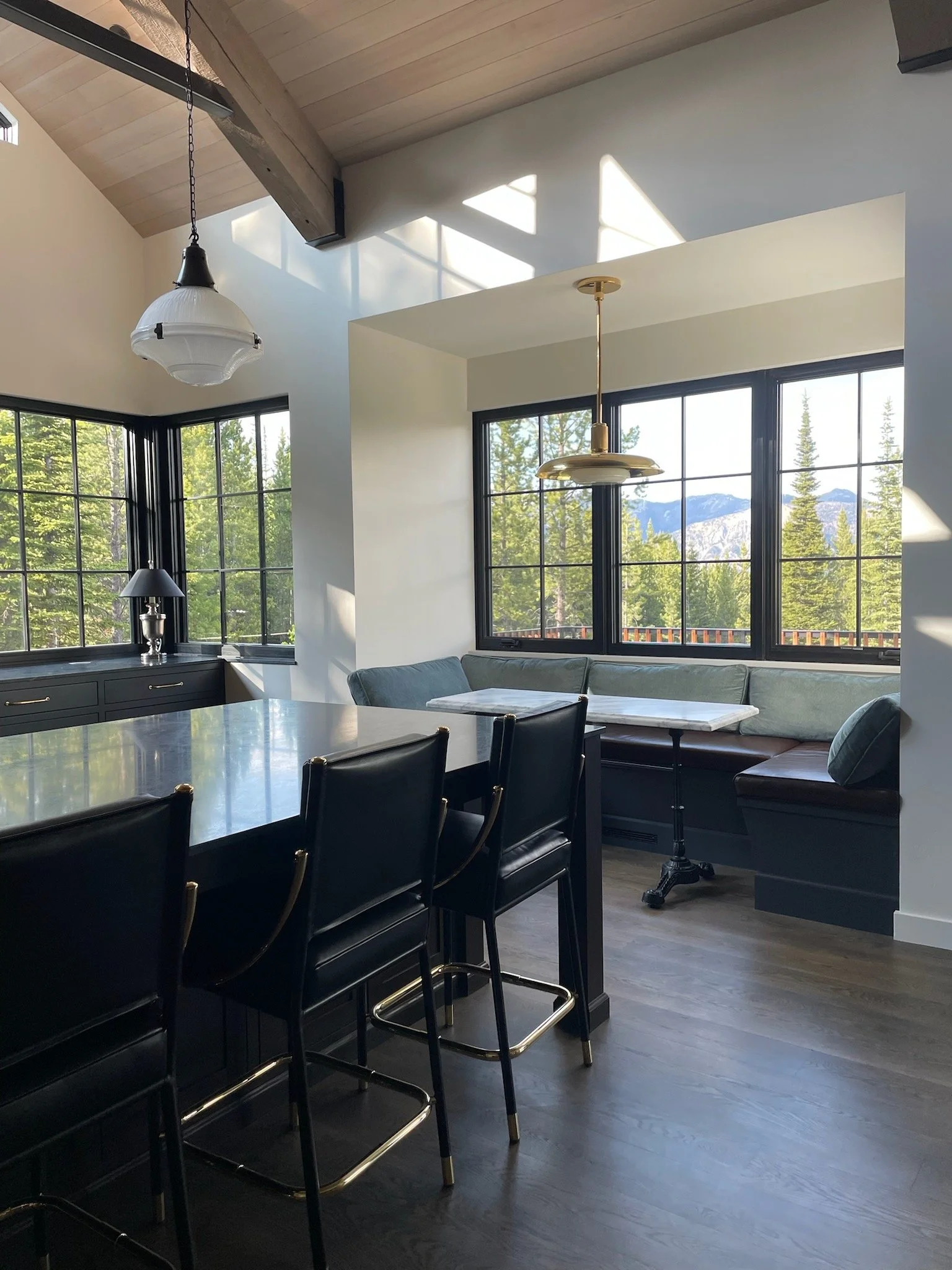 Modern Luxury Interior kitchen in Big Sky Montana with high ceilings, steel and wood beams, windows framing the Spanish Peaks mountains, leather stools, banquette designed by Hive Home