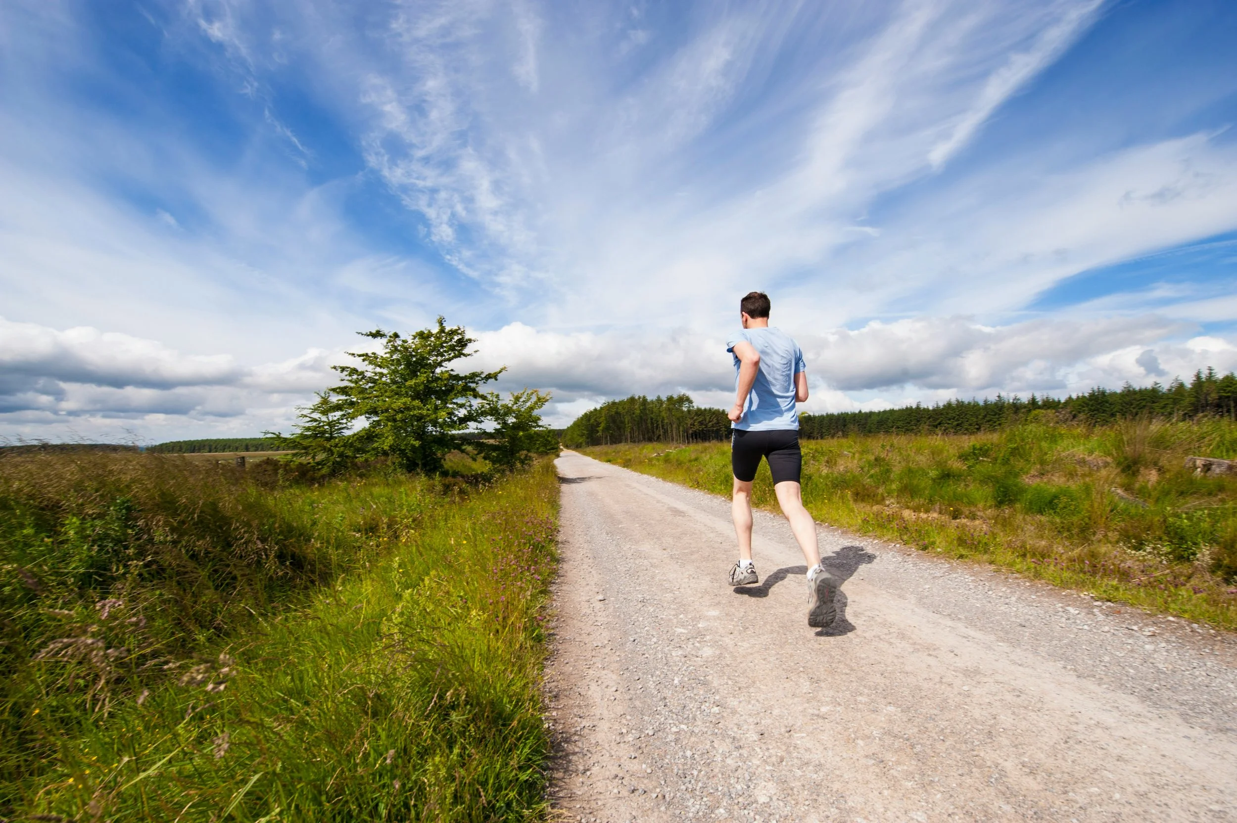 A man walking outdoors on a wooded trail