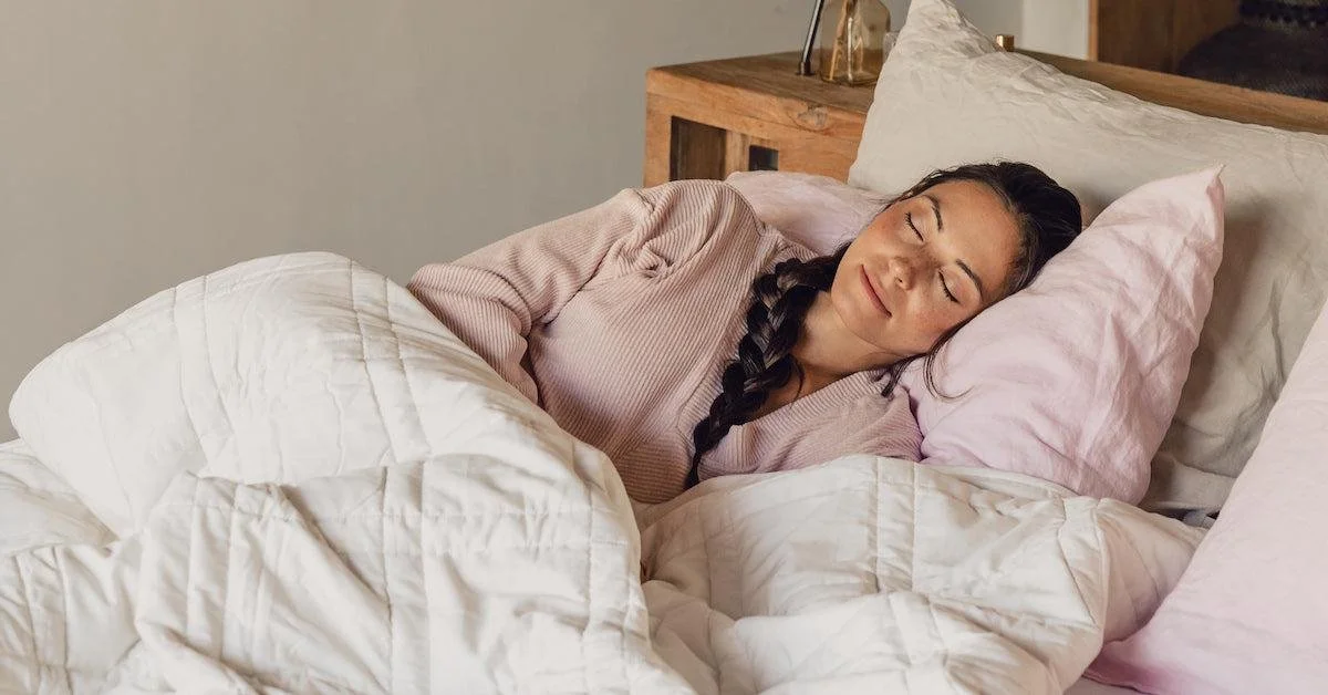 Woman peacefully sleeping on a bed with pastel linens.