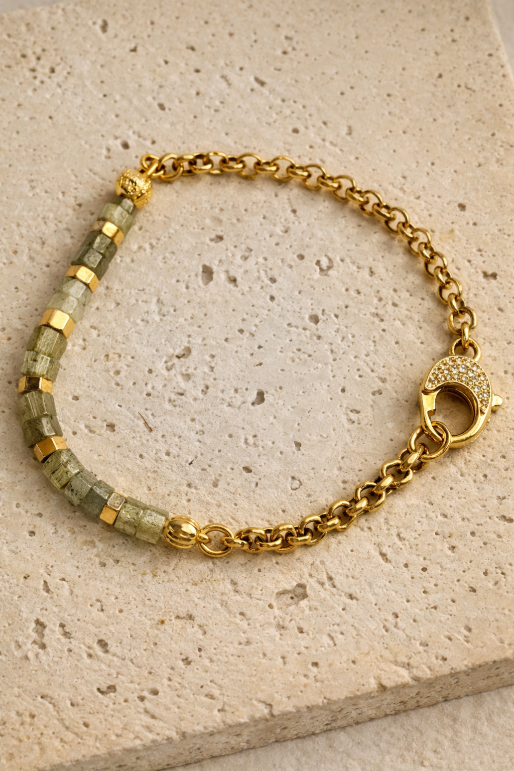 Labradorite beaded bracelet with gold detailing on neutral stone background