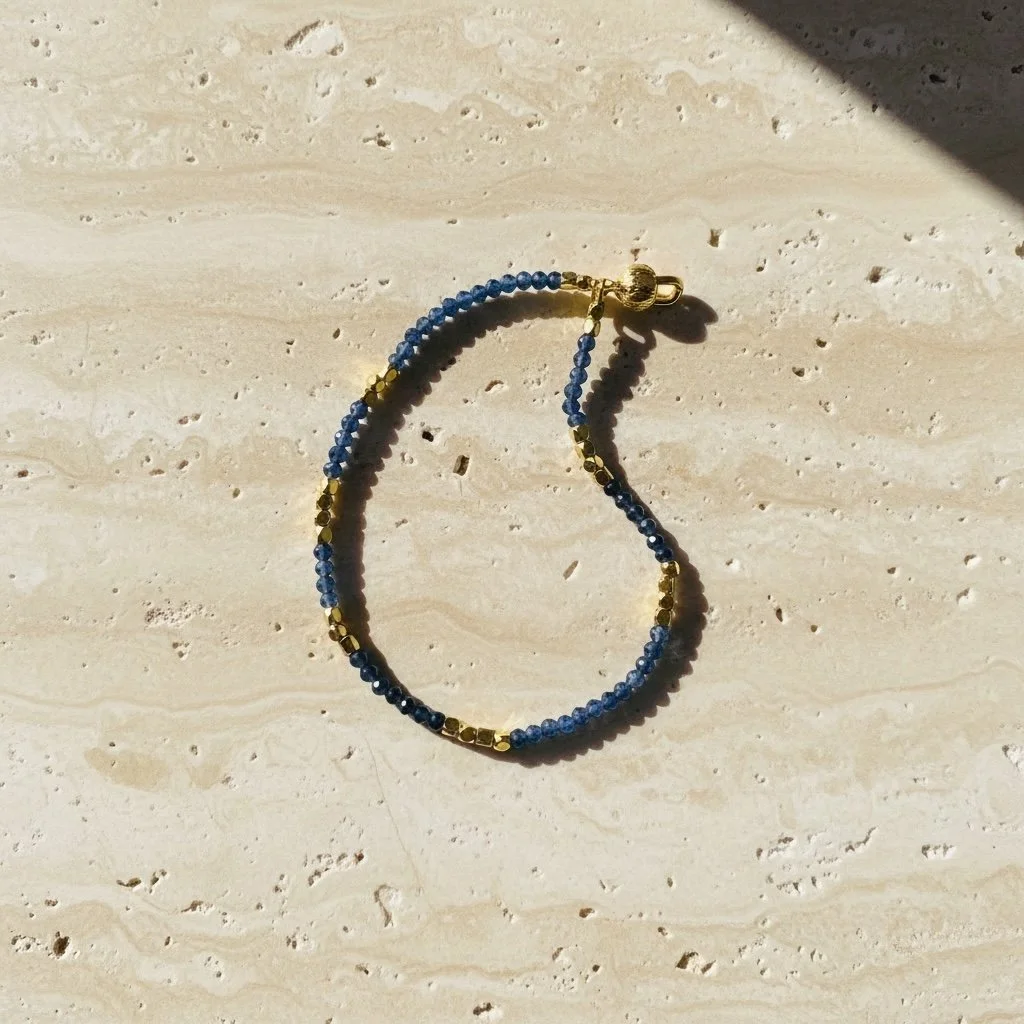 Sapphire bracelet with gold tone accents photographed on neutral background
