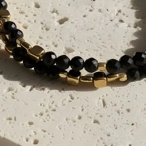 Glossy black bead bracelet with gold details photographed close-up
