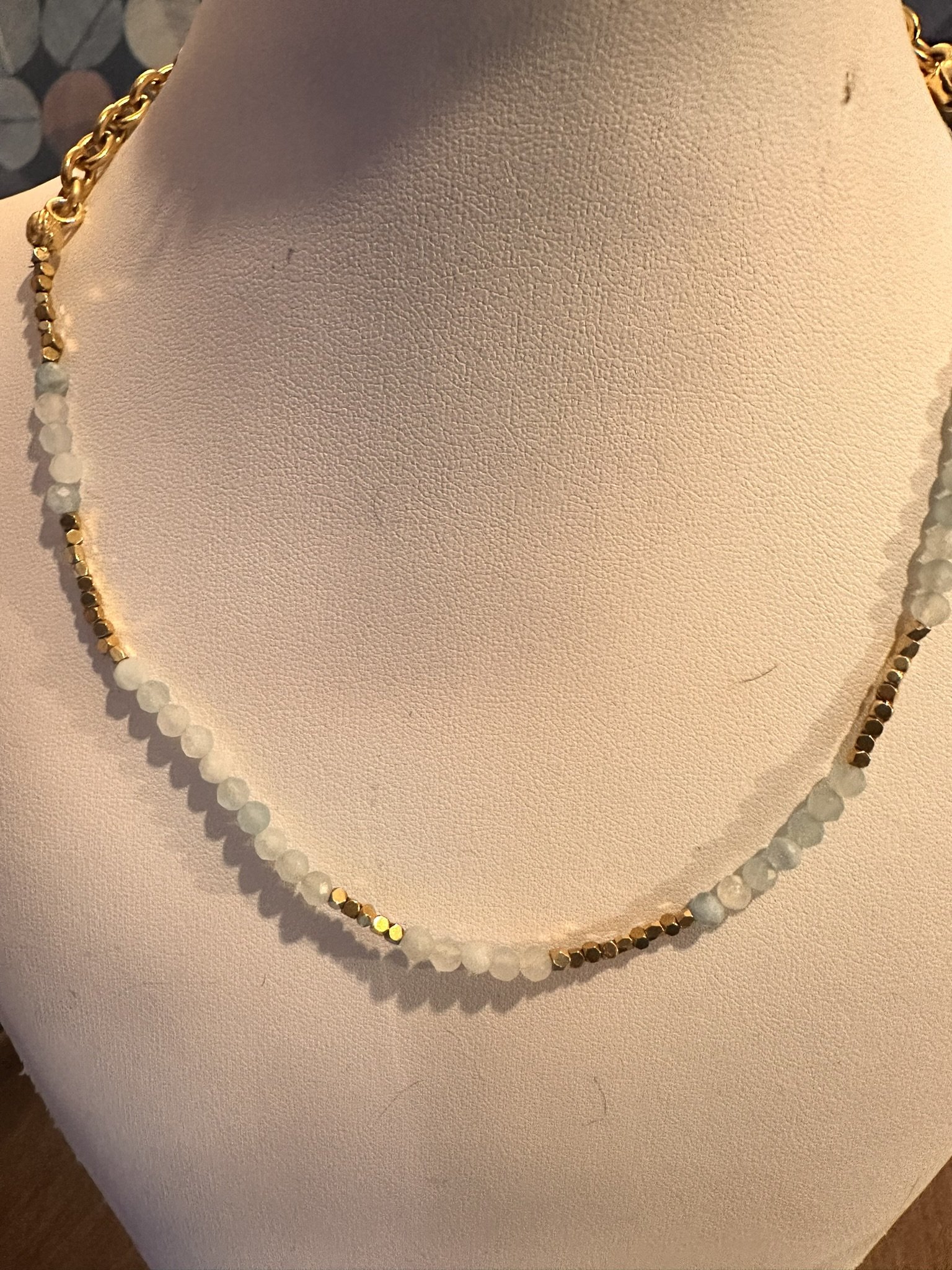 Aquamarine gemstone necklace on gold chain with gold bead detailing.