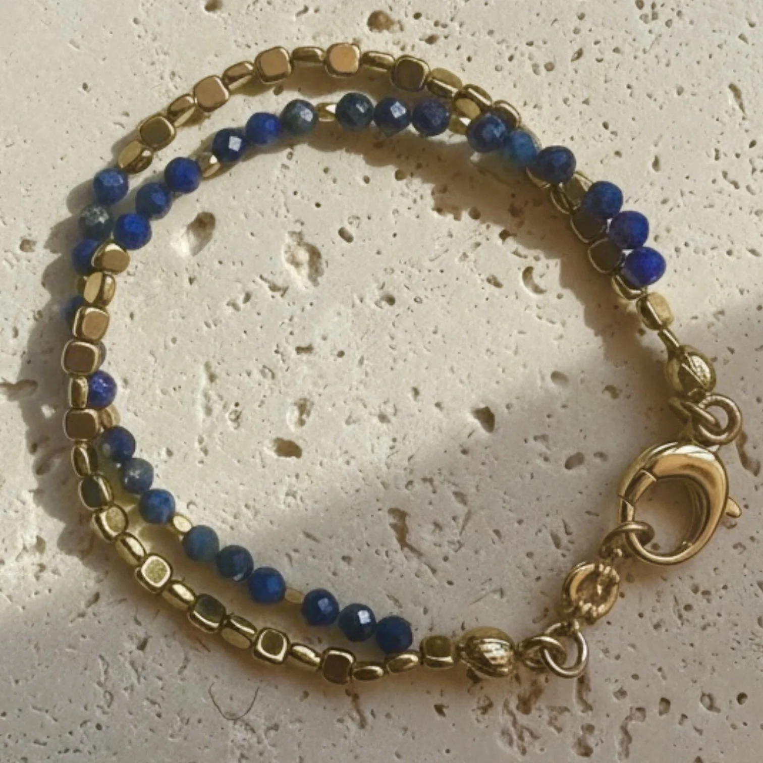 Lapis lazuli beaded bracelet with gold accents on neutral stone