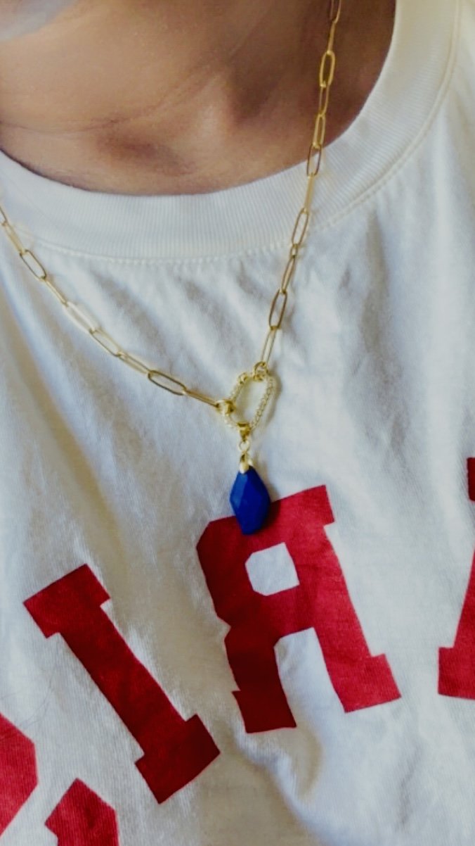 Caelia Necklace worn over white top, showing gold paperclip chain and CZ pavé carabiner with lapis lazuli pendant.