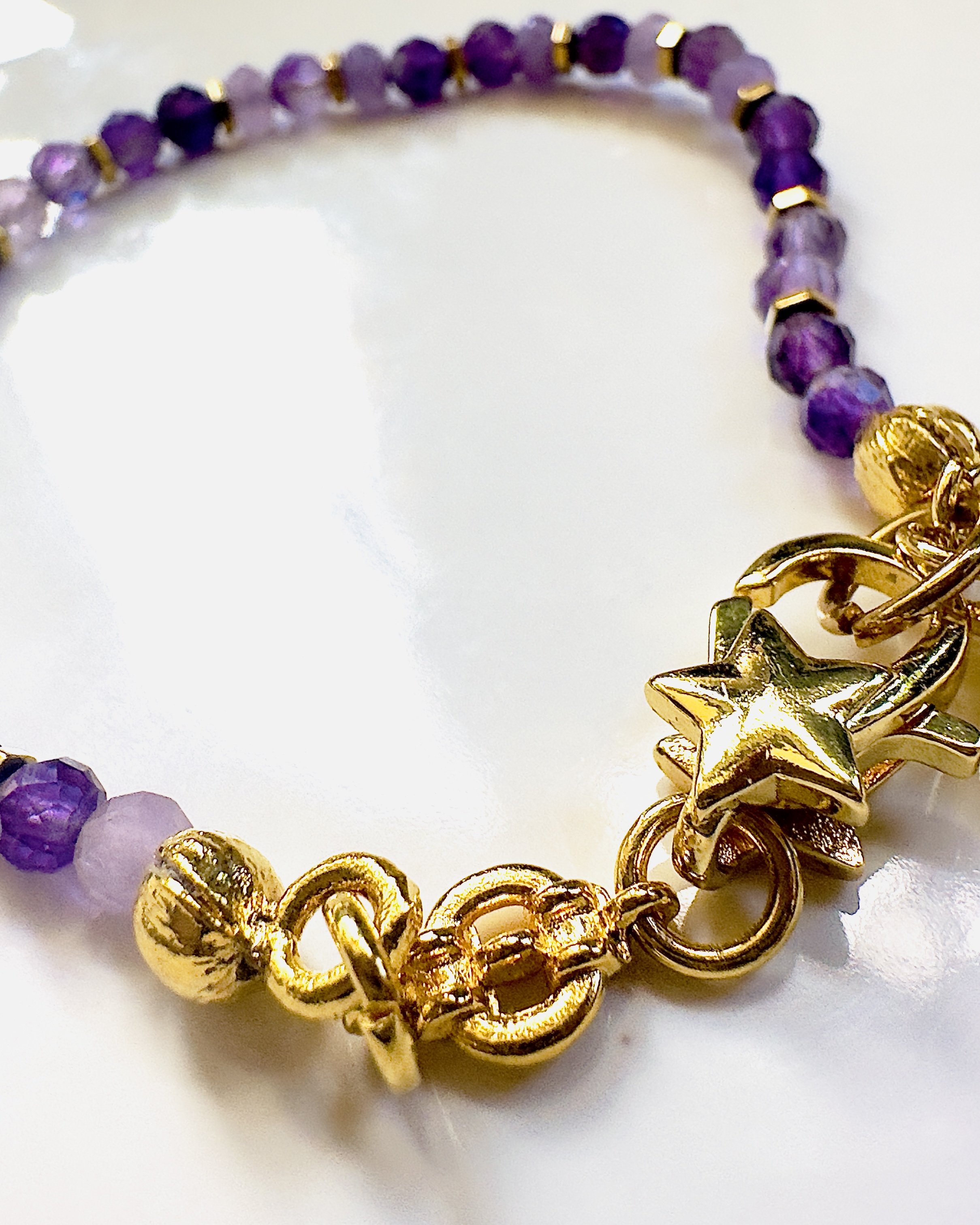 Handcrafted Amethyst Celeste Bracelet featuring radiant purple Amethyst beads, gold-plated spacers, and a celestial charm, symbolising serenity and spiritual wisdom.