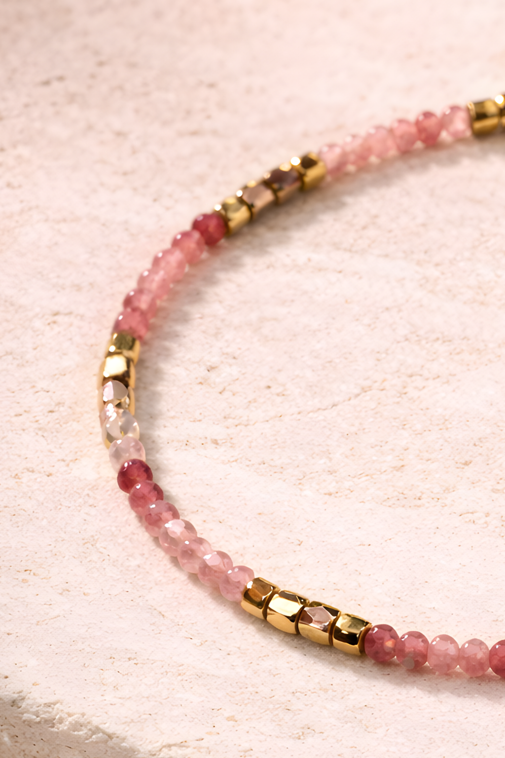 Rose quartz bracelet with gold tone accents photographed on neutral background