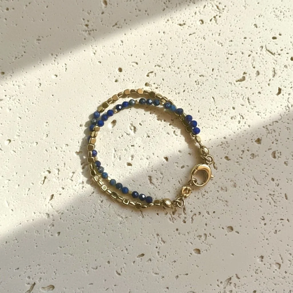 Lapis lazuli beaded bracelet with gold accents on neutral stone