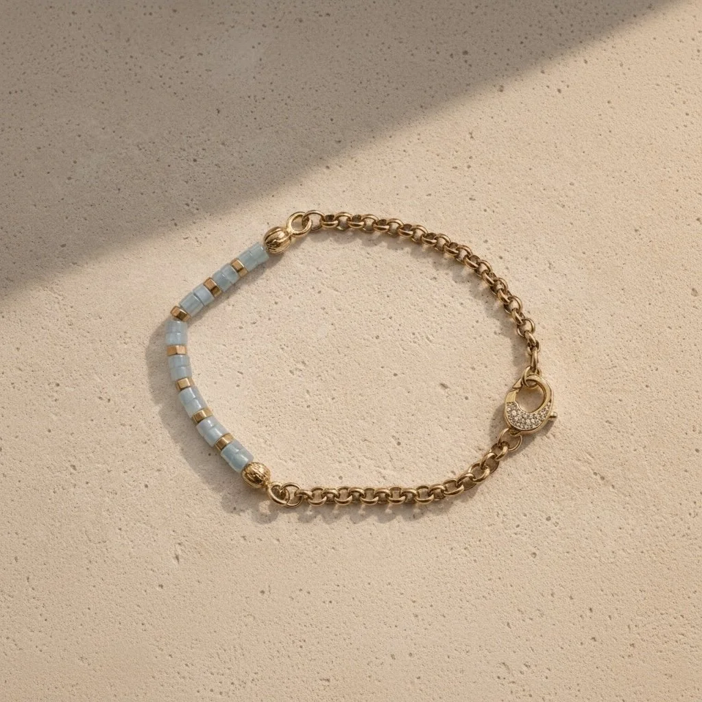 Aquamarine beaded bracelet with gold detailing on pale stone surface