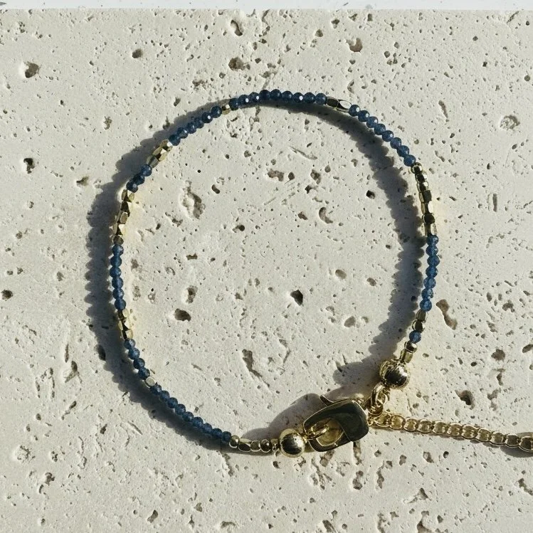 Sapphire bracelet with gold tone accents photographed on neutral background