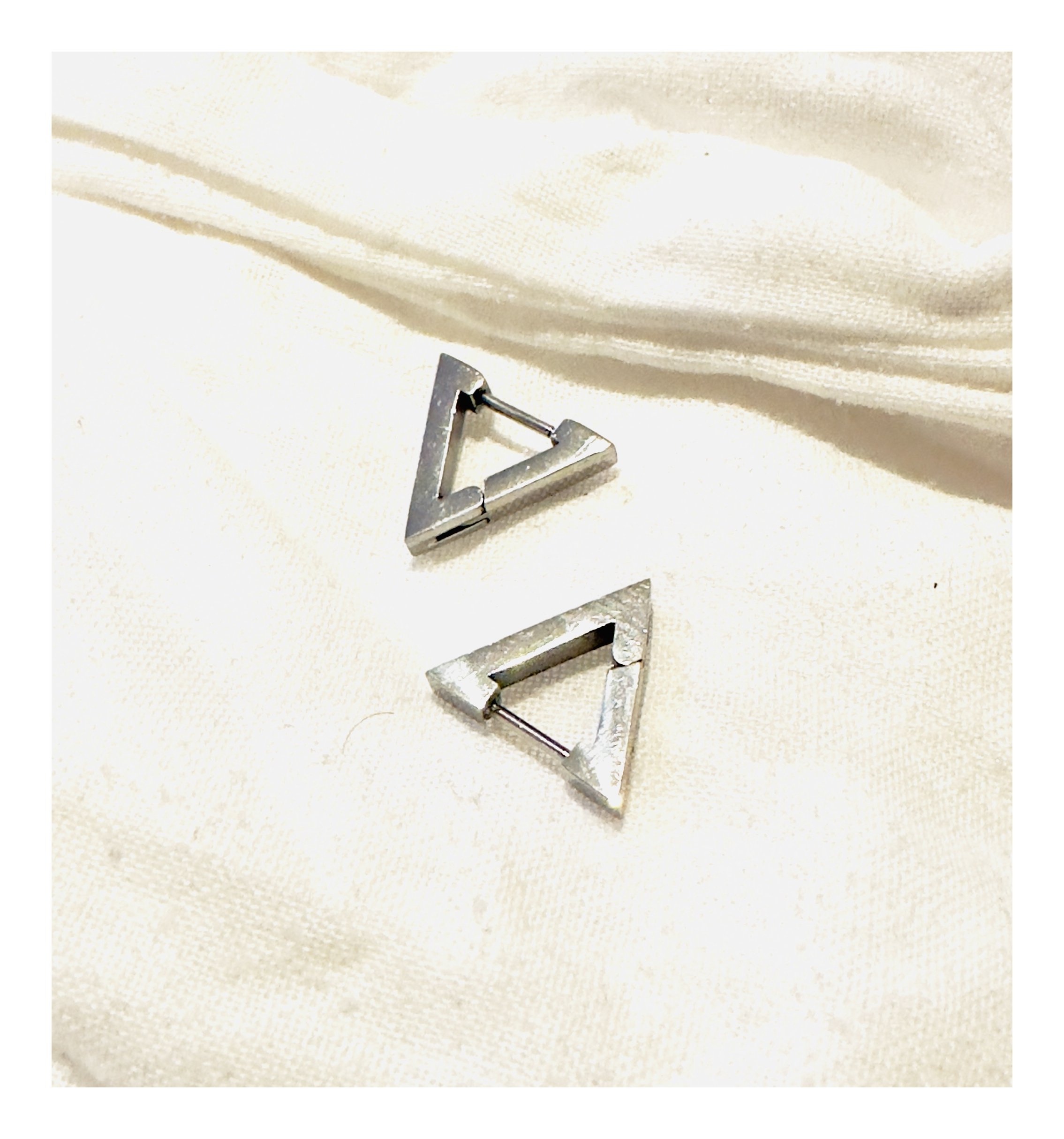 A captivating close-up view of the Silver Toned Titanium Steel Giza Huggie Earrings, showcasing the minimalist sophistication tangible in every angle and gleam