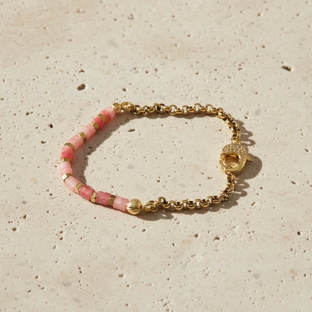 Rose quartz beaded bracelet with gold detailing on pale stone surface